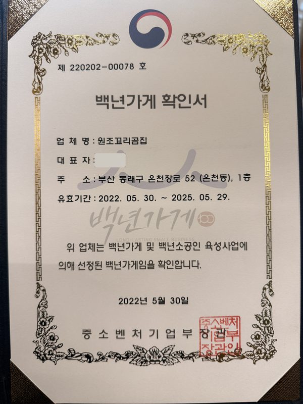 중소벤처기업부 장관 명의의 백년가게 확인서. 업체명 원조꼬리곰집, 주소 부산 동래구 온천장로 52 (온천동) 1층, 발급일 2022년 5월 30일이 적혀 있다.