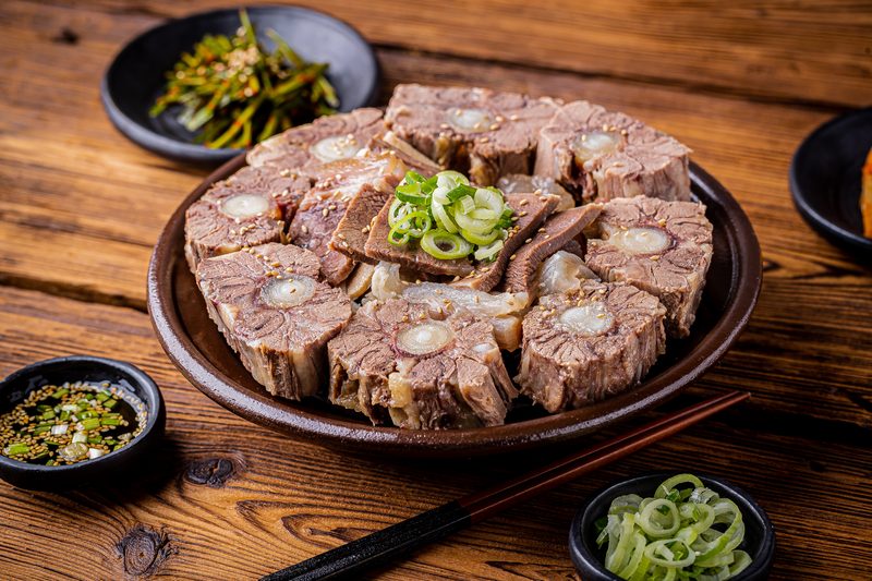 둥근 접시에 담은 모듬수육. 단면에 뼈가 보이는 꼬리 토막이 가장자리에, 얇게 썬 고기가 가운데에 놓여 있다.